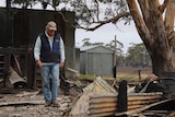 Cattle farmer Brad Gilmour looks at fire damage.