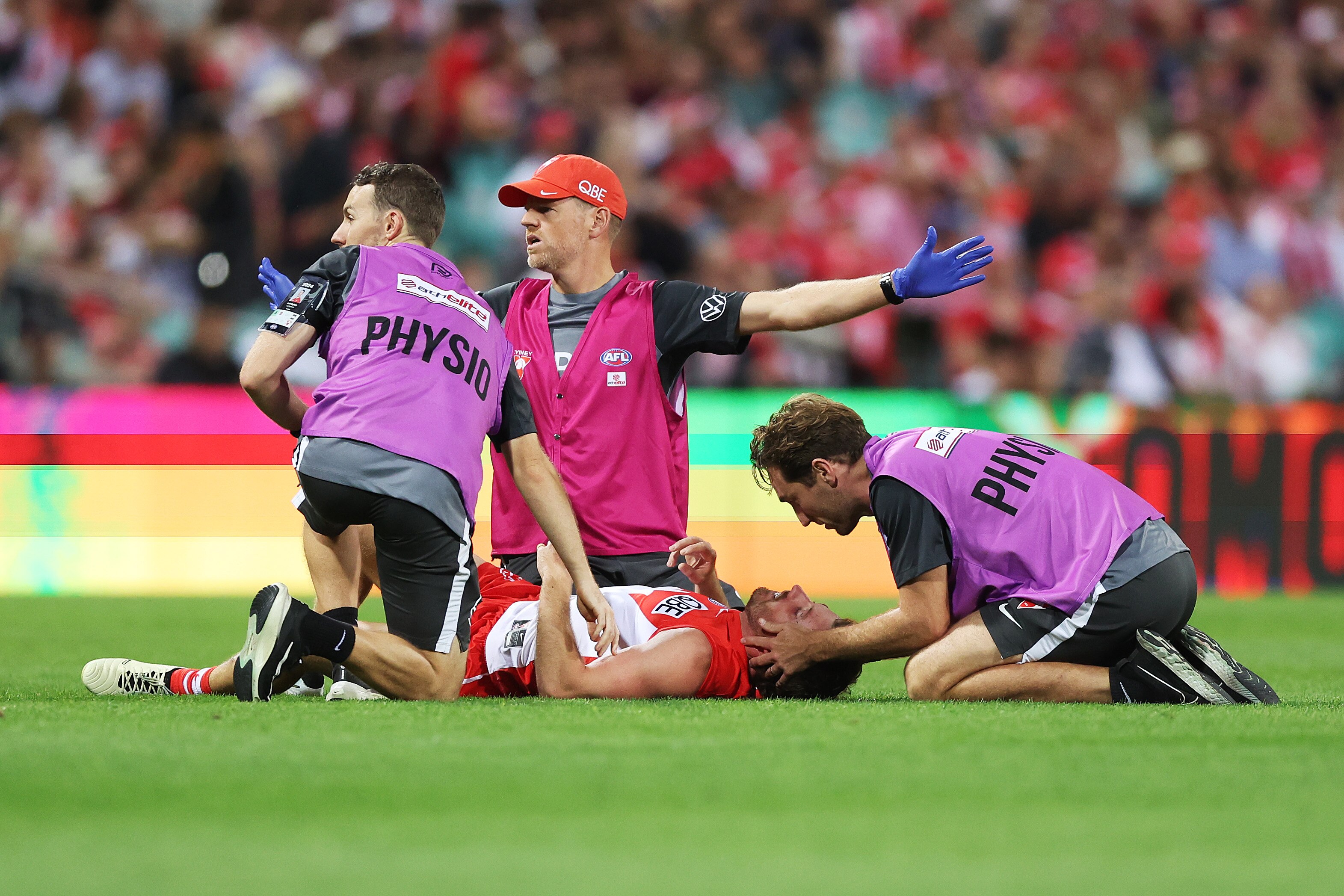 A Sydney Swans player receives medical attention after a collision in an AFL match against Essendon.
