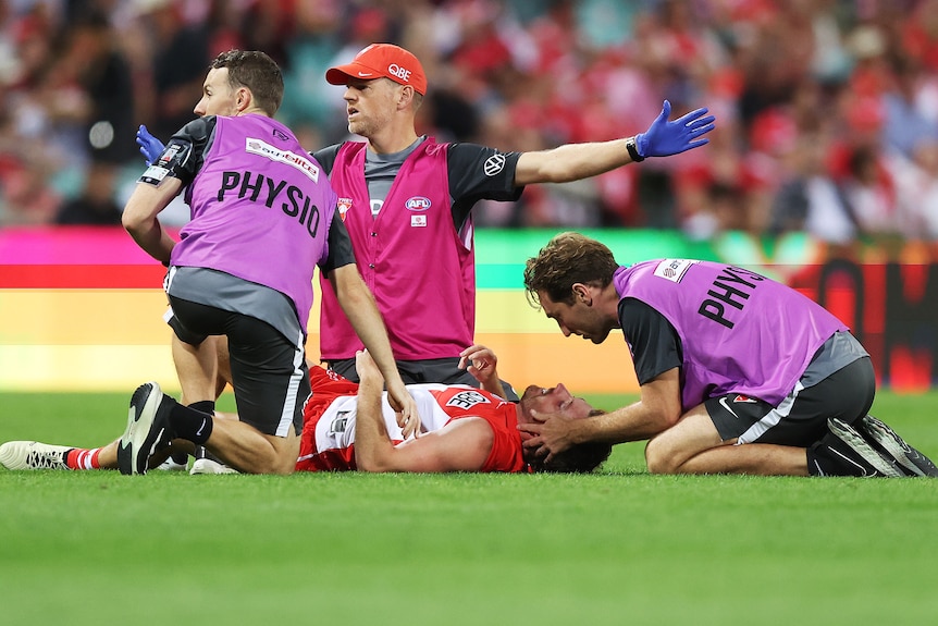 A Sydney Swans player receives medical attention after a collision in an AFL match against Essendon.