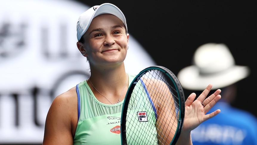 Female tennis player smiling after winning a match while holding her racket