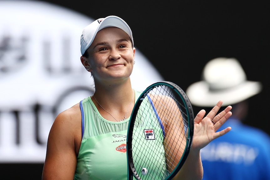 Female tennis player smiling after winning a match while holding her racket