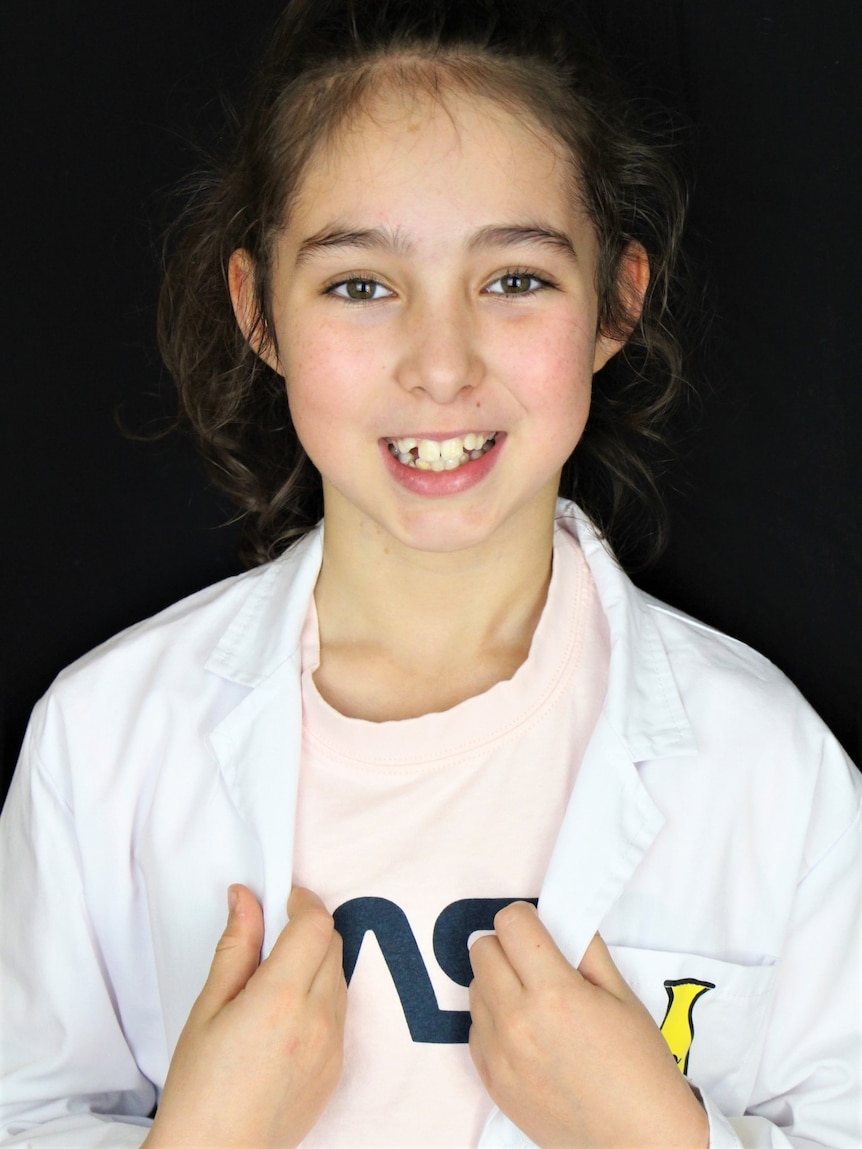 A young girl in a lab coat smiling