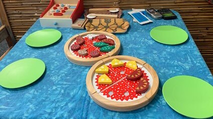 Toy pizzas on a table with plates, ready to be served