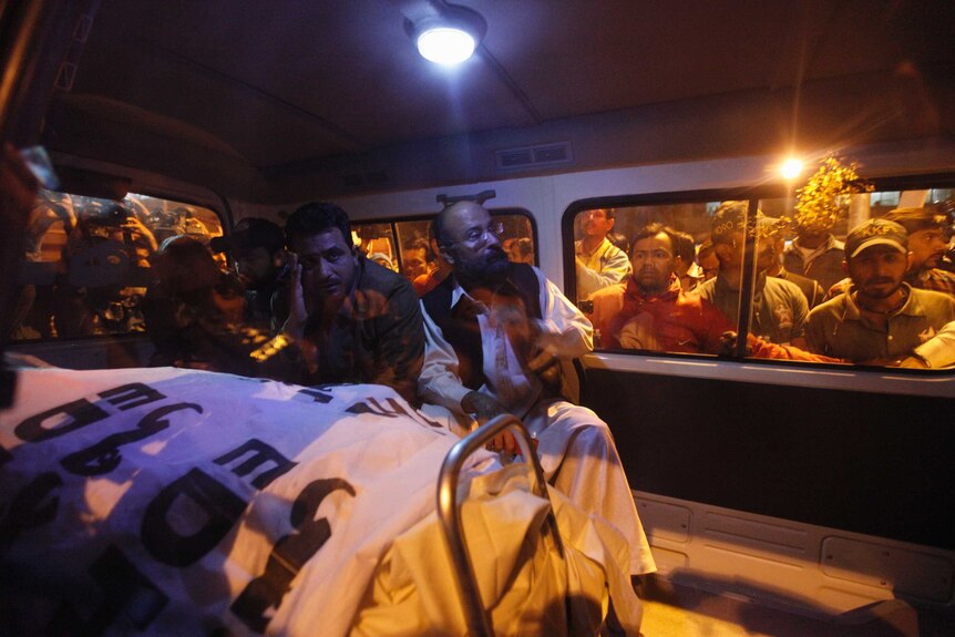 Mourners gather around the body of Chaudry Aslam