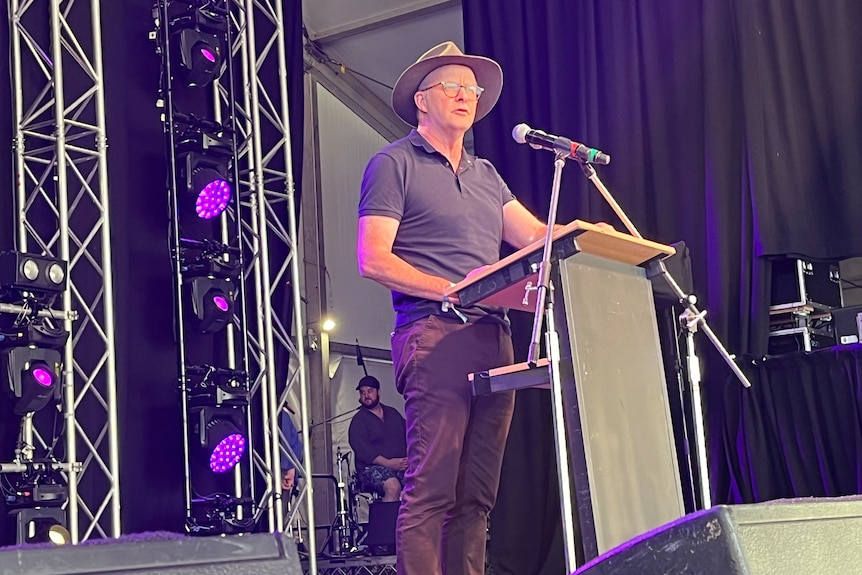 Anthony Albanese wearing a wide-brimmed hat stands at a lectern and delivers a speech at Woodford Folk Festival