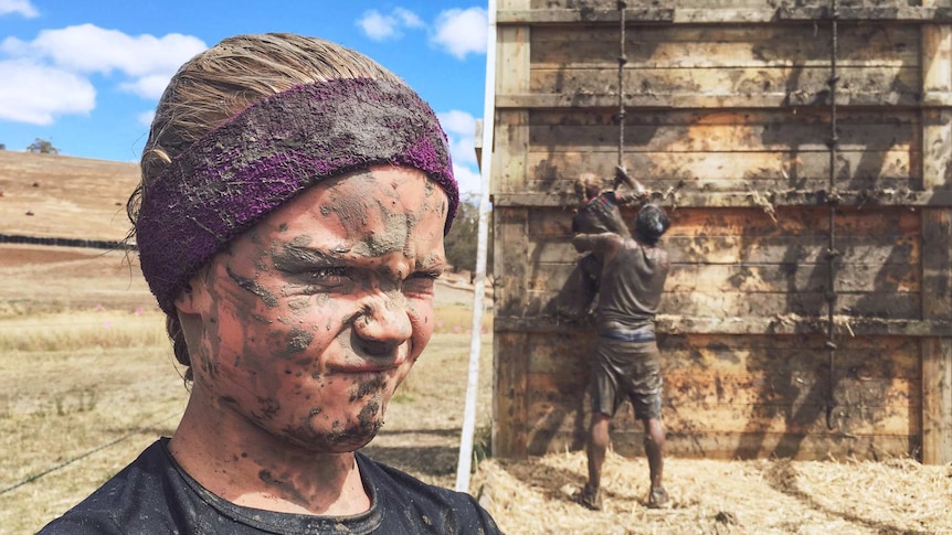 a boy covered in mud after taking part in an obstacle course.