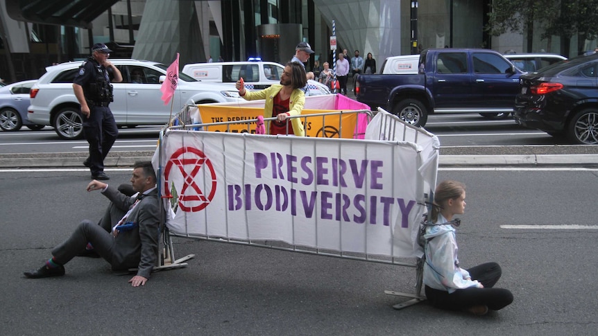 Extinction Rebellion protesters chained to barricades on a main road in Brisbane
