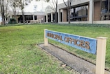 A sign that reads "municipal offices", on the grass outside a building.