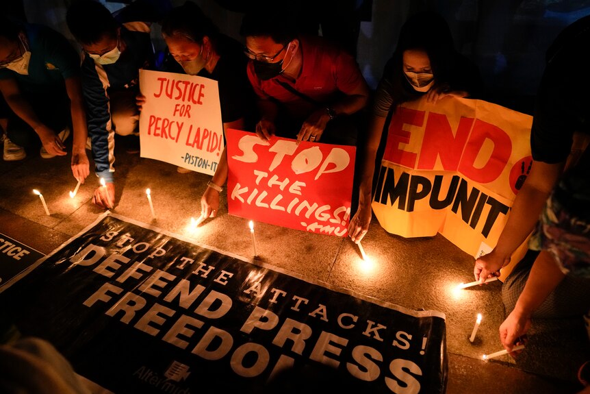Activists light candle beside slogans as they condemn the killing of Filipino journalist Percival Mabasa.