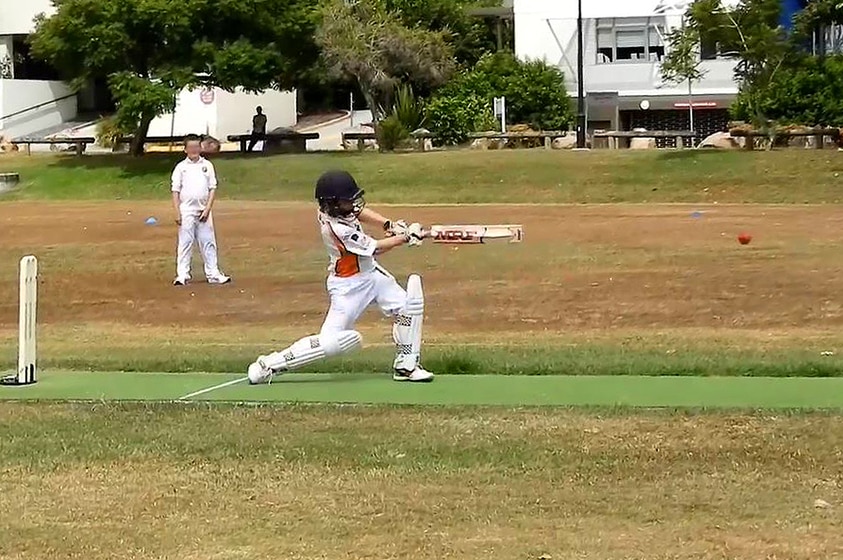 A young boy bats in a cricket game as another boy watches