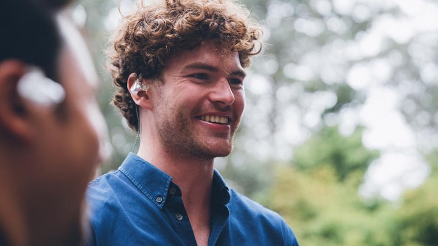 A portrait of a grinning Vance Joy performing live