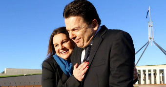 Jackie Lambie hugs Nick Xenophon outside Parliament House in Canberra, the flagpole visible behind them.