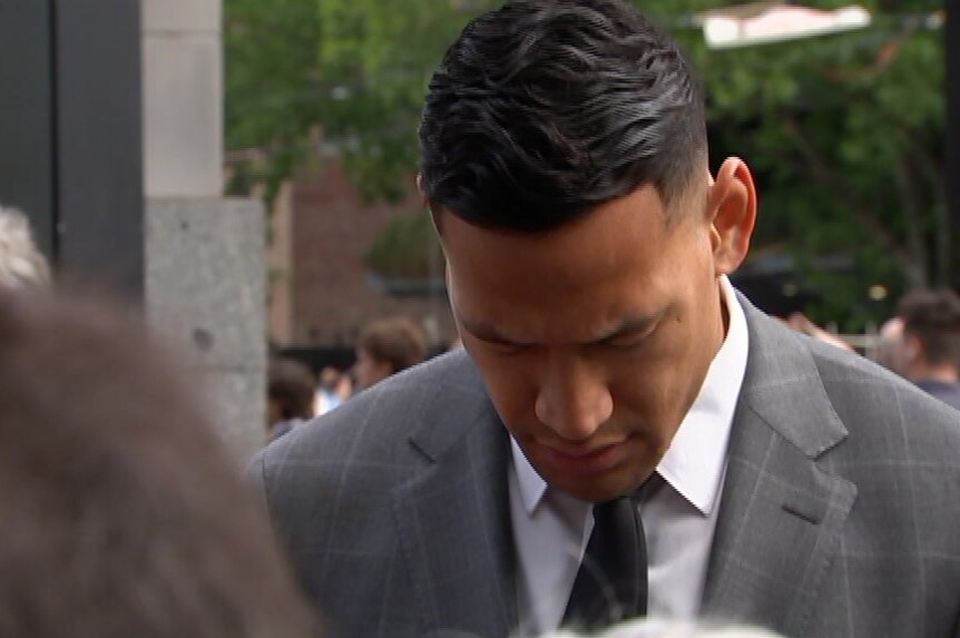 Israel Folau prays outside Fedeal Court with his head down and eyes closed on a grey day.