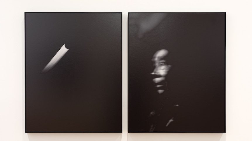 Two black-and-white photographs hanging on a wall, once includes the blurred face of a person and the other includes moonlight.