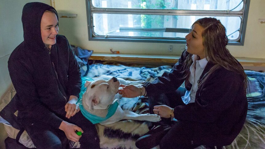 Breanna on her bed with her dog and boyfriend.