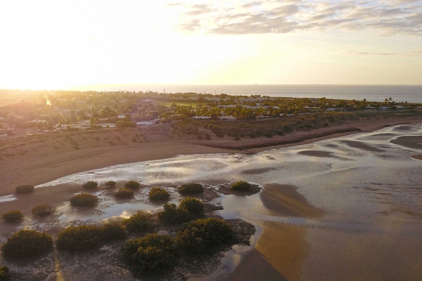 An aerial picture of a coastal area with the tide out as the sun sets.