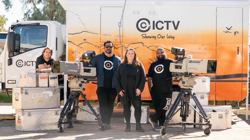 Three men and a woman standing with cameras and equipment in front of a TV van with ICTV on side.