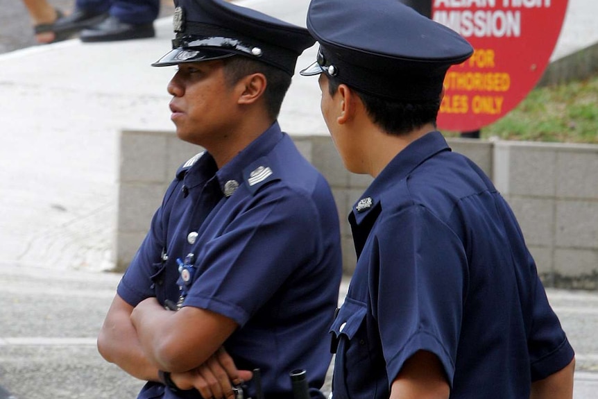 Singaporean police officers stand in the street.