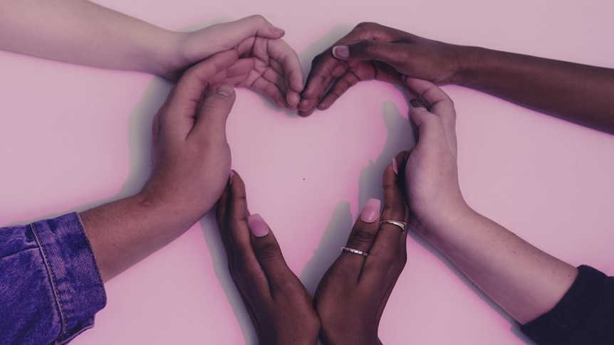 People form a love heart with their hands.