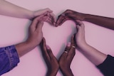 People form a love heart with their hands.