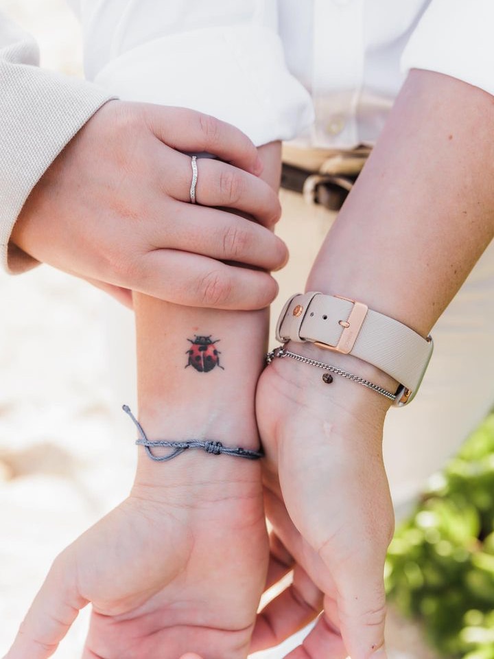 Jonassen holds her wrists together. On the right side is a ladybug tattoo and on the left is a real-life ladybug. 