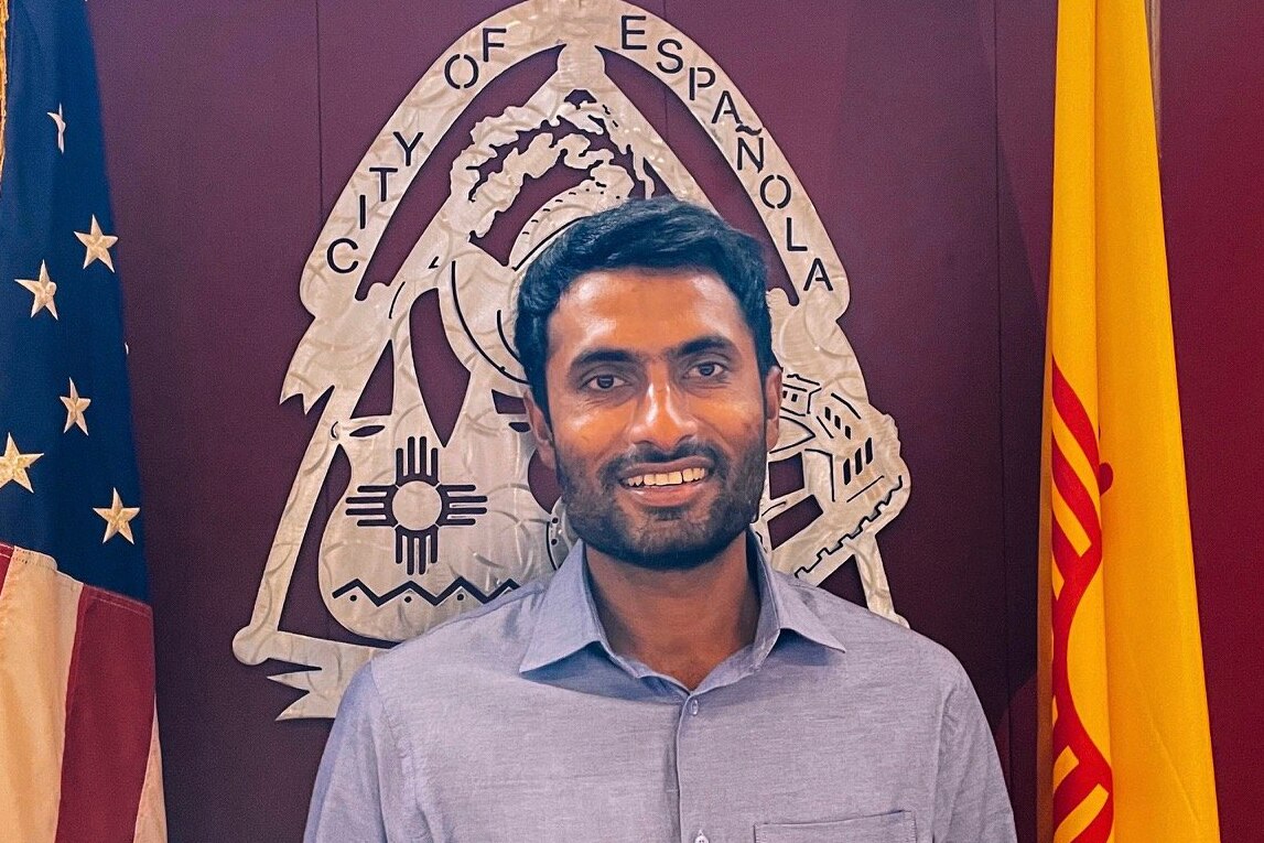 Man smiles in front of City of Espa&ntilde;ola crest.