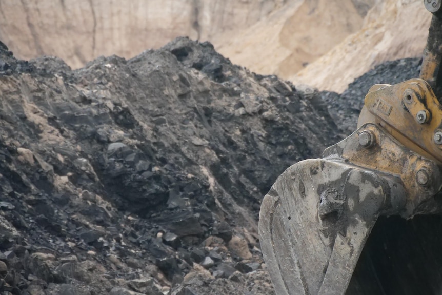 A mountain of coal and a heavy machine is visible in the foreground.