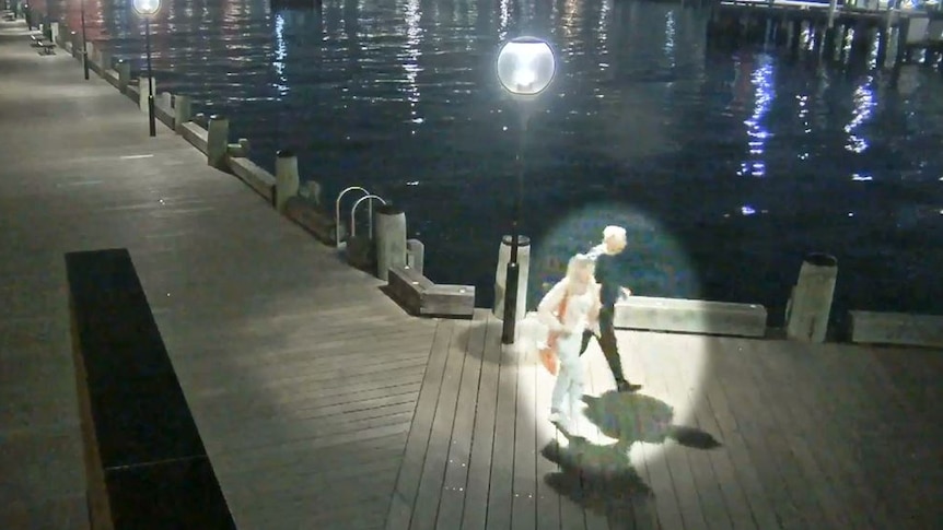 a man and woman walking along a dock walkway