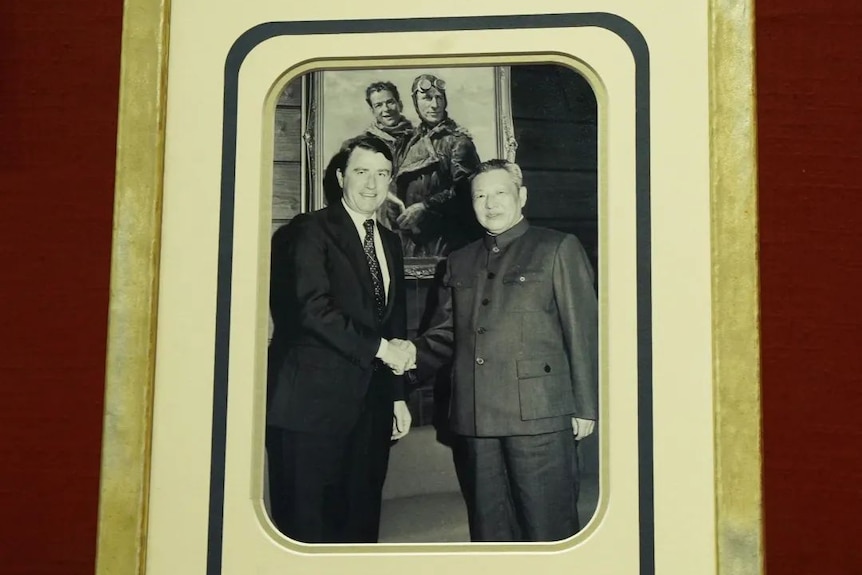 An old black and white photo showing Xi Zhongxun and Neville Wran shaking hands. 