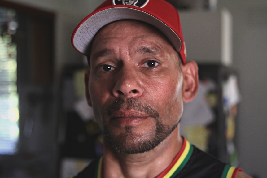 Close up of Aboriginal man wearing a red cap in a kitchen. 