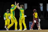 Two Australians do a double high-five to celebrate a West Indies wicket as the batsman trudges off in a T20I.