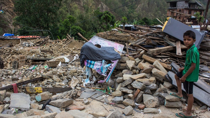 Boy looks at destroyed home in Nepal