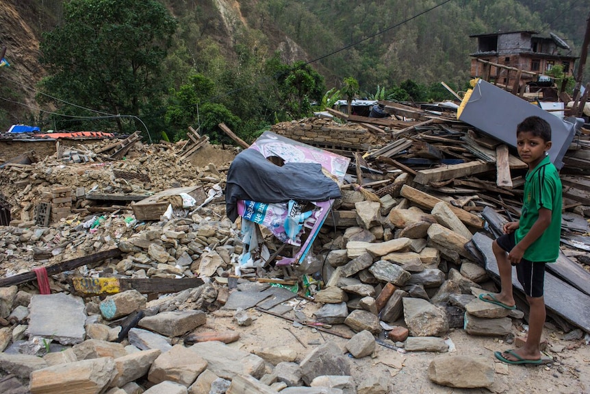 Boy looks at destroyed home in Nepal