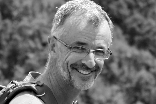 A black and white photo of a man wearing glasses and smiling