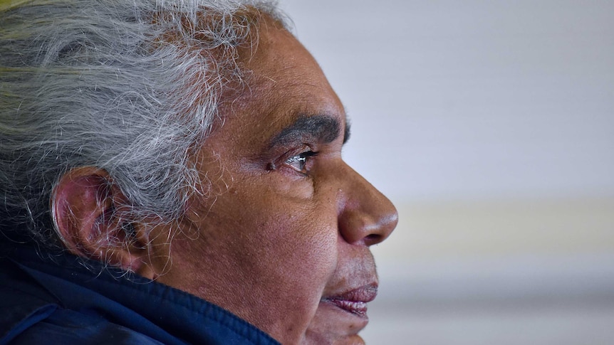 A close up of an Aboriginal woman.  She has white hair and tears in her eyes.