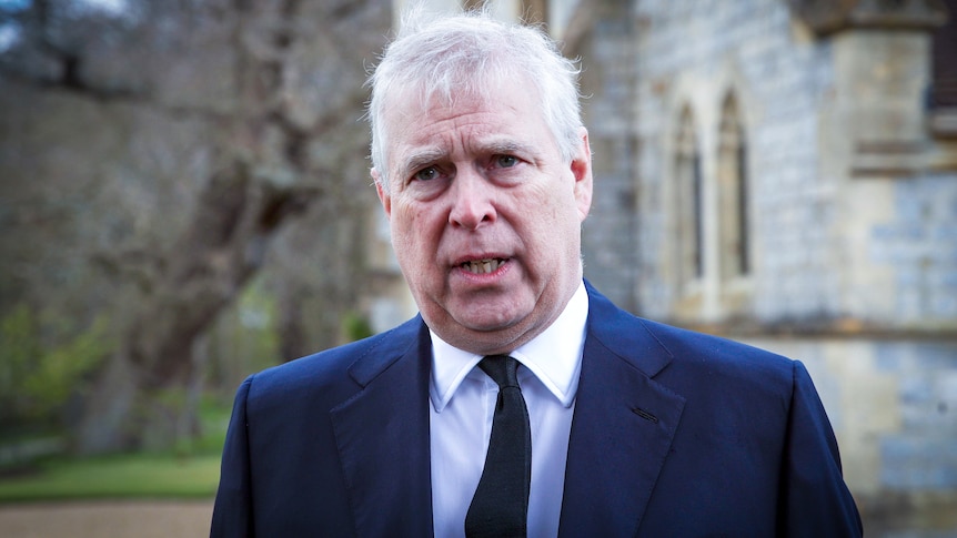 Prince Andrew in a suit standing outside a church 