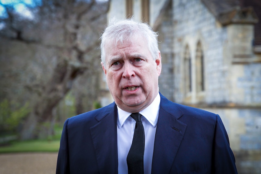 Prince Andrew in a suit standing outside a church 