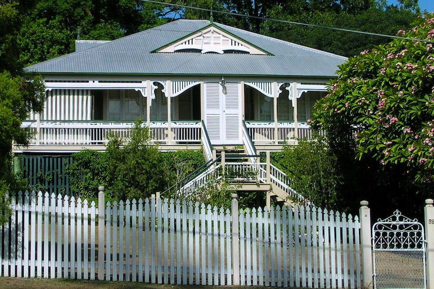 Queenslander house with a white picket fence.