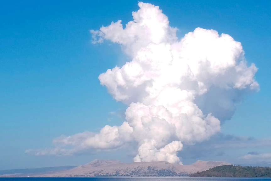 A volcano spews white steam.