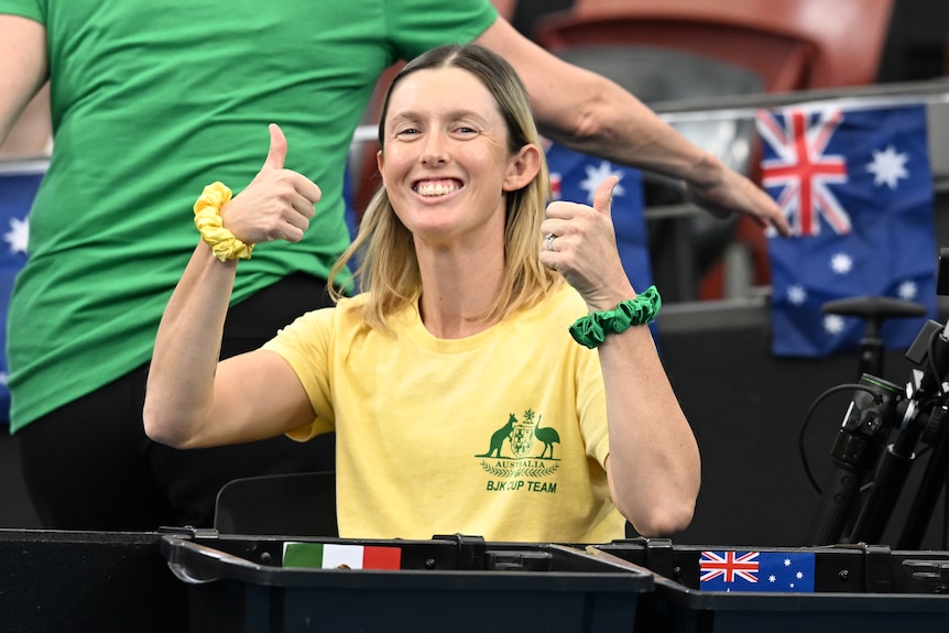 Injured Australian tennis player Storm Hunter smiles and gives two thumbs up as she sits courtside in Brisbane.