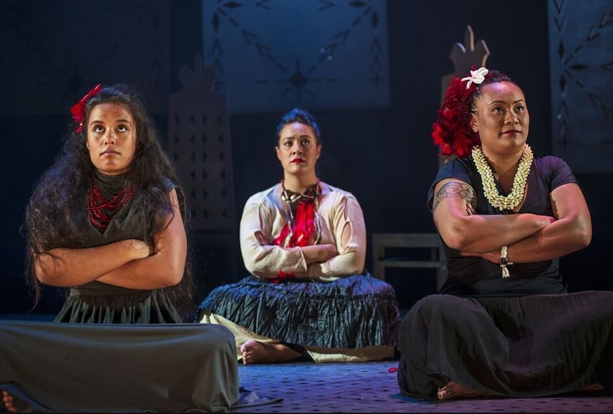 Three women of Samoan heritage sit on stage performing play titled, Wild Dogs Under my skirt. 