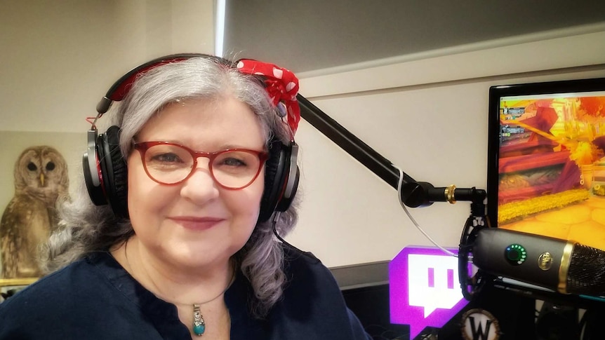 A woman wearing headphones next to a computer.