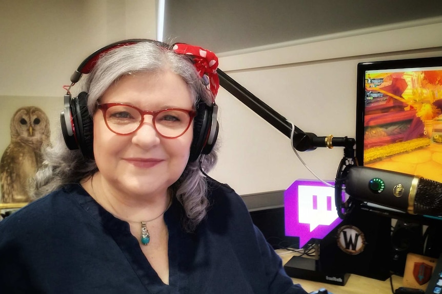 A woman wearing headphones next to a computer.