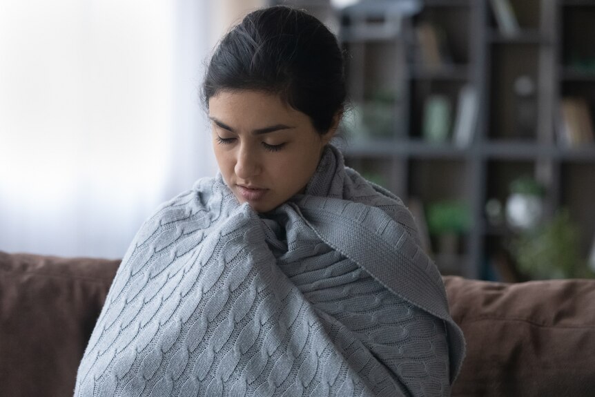 A grey blanket wrapped around a young woman