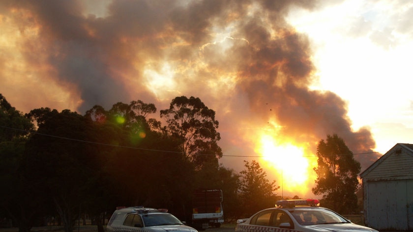 Police cars sit outside houses being threatened by the Gippsland bushfires