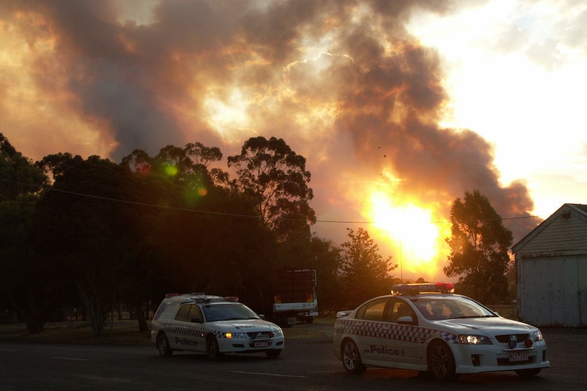 Police cars sit outside houses being threatened by the Gippsland bushfires