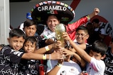 A man wearing a sombrero and six children pose for a photo with the FIFA World Cup trophy.