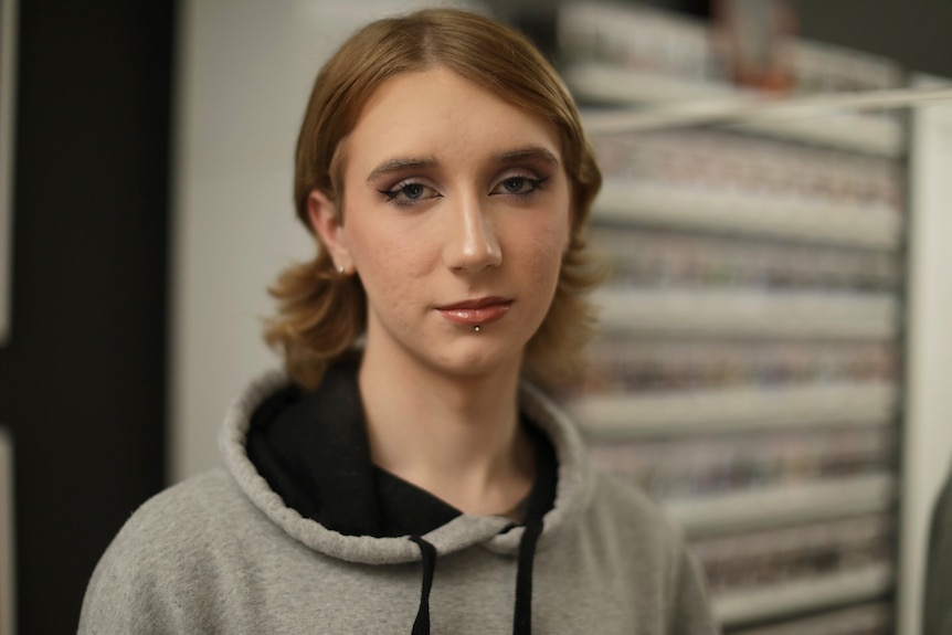 A teenage girl with eye liner and makeup, looks at the camera with a neutral expression.