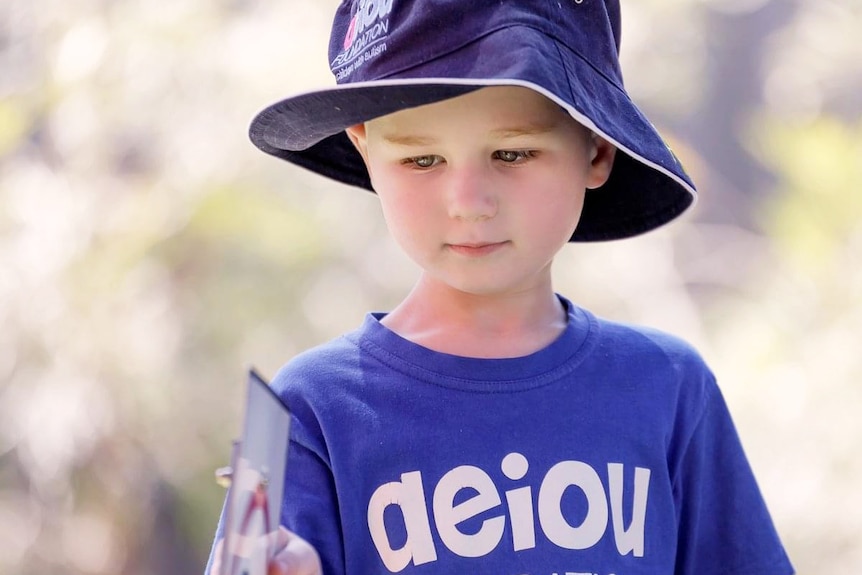 William Wallington stands with a blue hat and AEIOU T-shift on