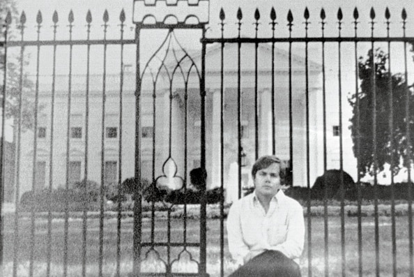 The would-be assassin of Ronald Reagan, John Hinckley, sits on a fence surround the White House